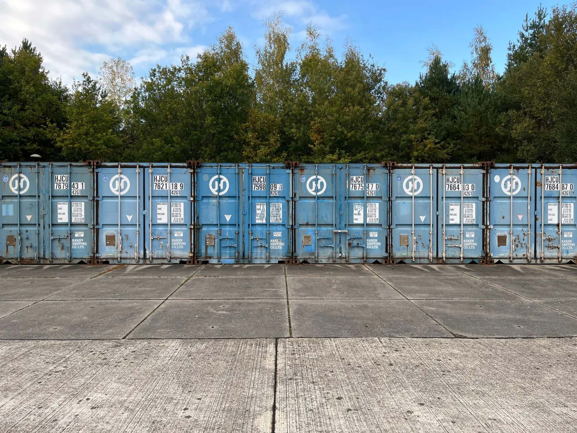 A secure storage yard — a row of steel containers on hardstanding under a blue sky in the North West
